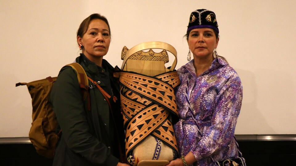 Deux femmes tiennent un porte-bébé traditionnel autochtone.