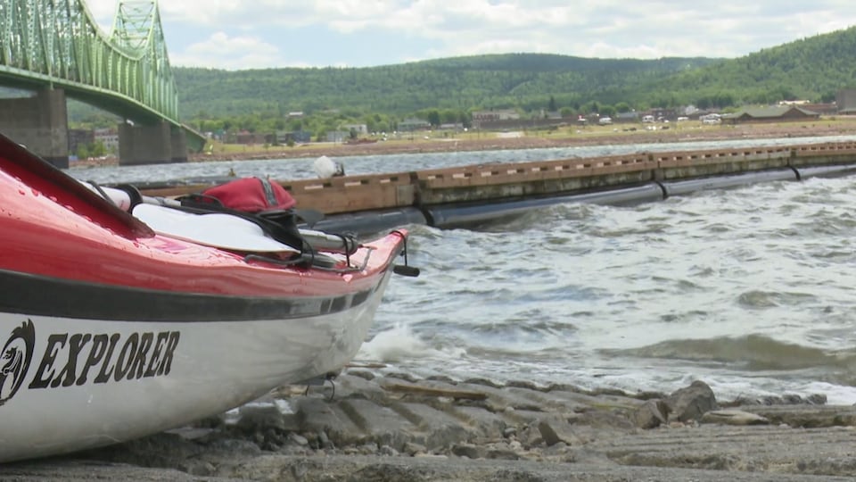 On voit un kayak de très près. Il est en bordure d'un plan d'eau, près de quai.