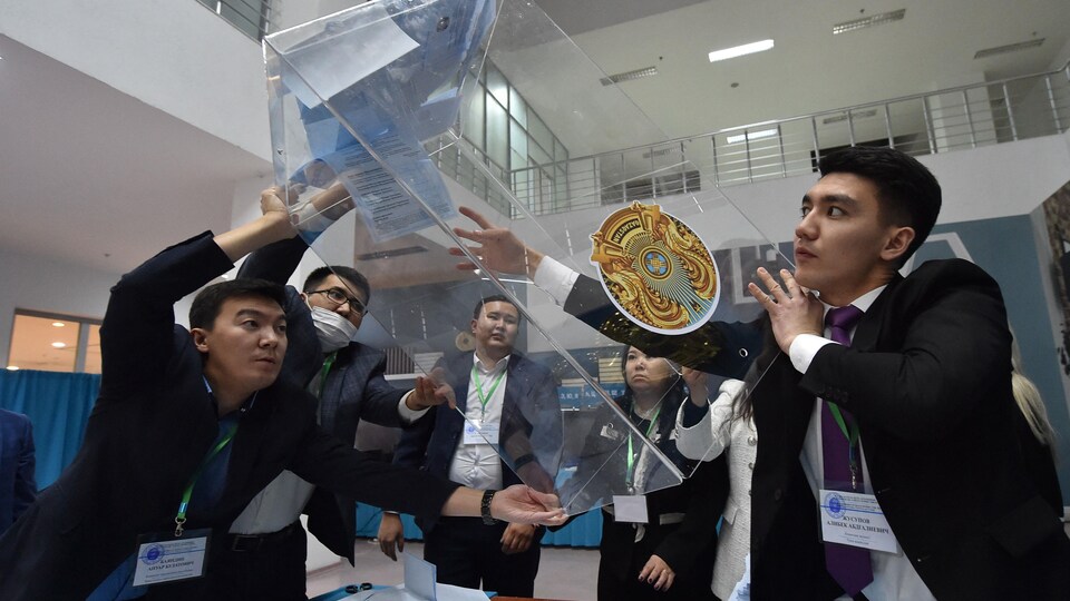 Des gens vident une boîte de scrutin dans un bureau électoral du Kazakhstan.