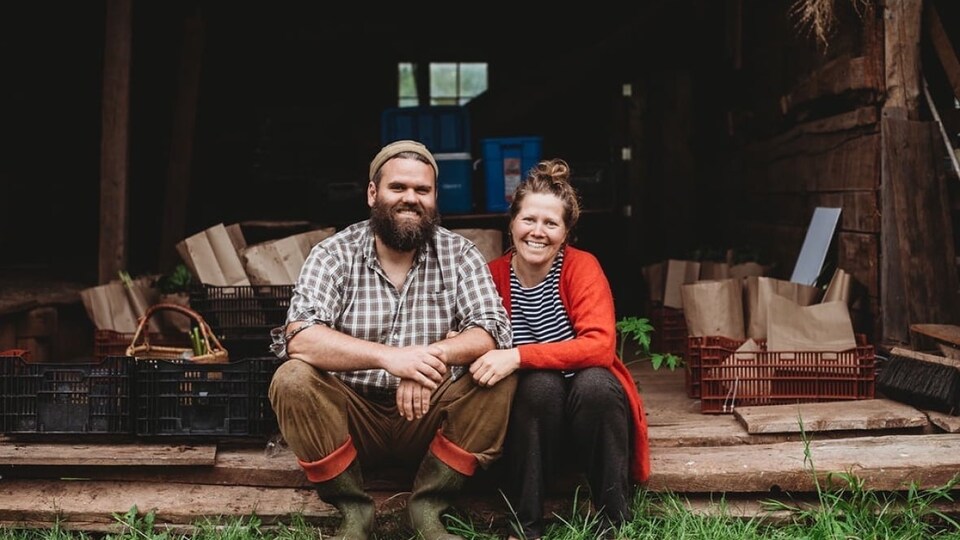 Les deux sourient assis dans une grange.
