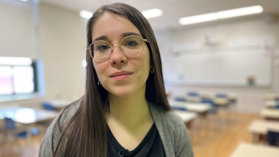 Kelly Laramée est assise sur un bureau dans la classe d'une école secondaire. 
