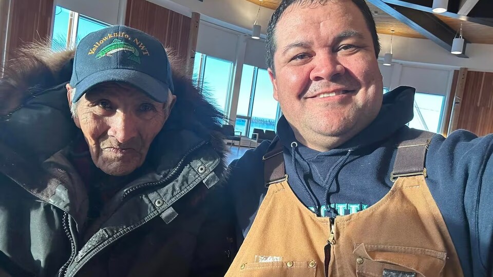 Deux hommes sourient en prenant un égoportrait.