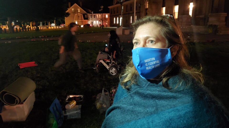 Kerri Froc porte un masque sur lequel est écrit « L'avortement est un soin de santé essentiel ».