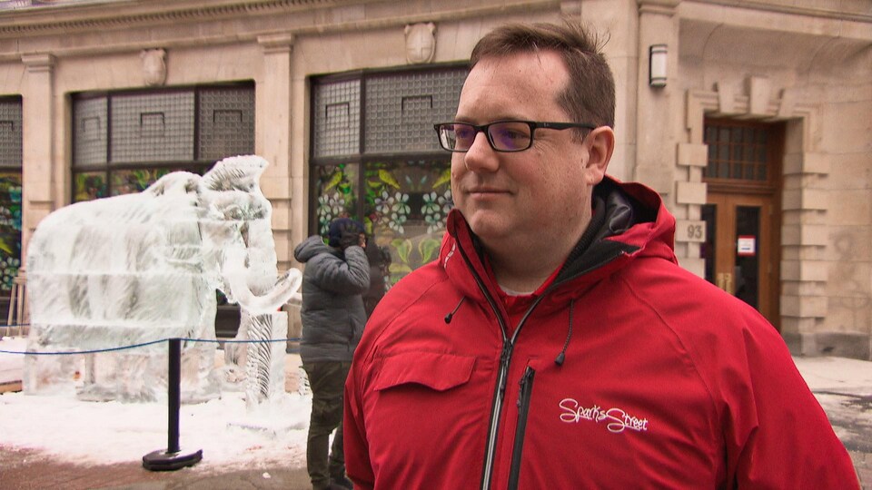 Kevin McHale en entrevue sur la rue Sparks, devant une sculpture de glace en forme de mammouth.