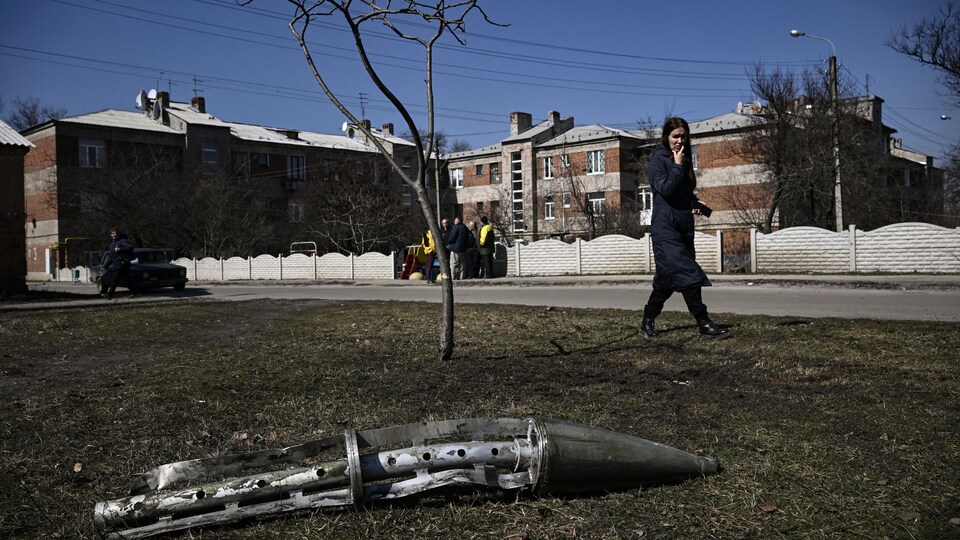Une femme regarde un fragment de roquette à fragmentation à Kharkiv.