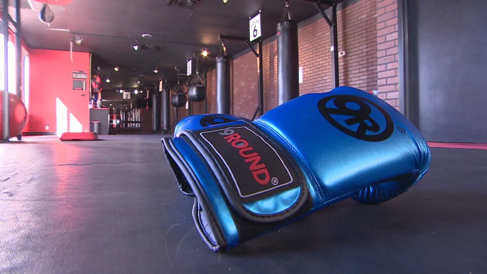 Un gant de boxe sur lequel est écrit «9Round» par terre dans une salle de sport.
