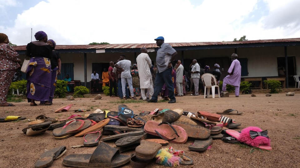 Des sandales empilées devant une école.
