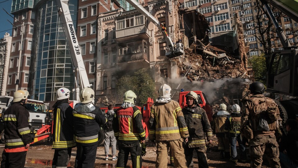 Des pompiers ukrainiens travaillent sur un bâtiment détruit.