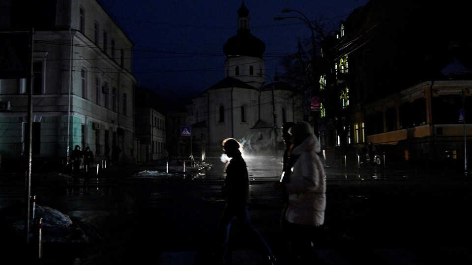 Des personnes qui marchent sur une rue sombre.