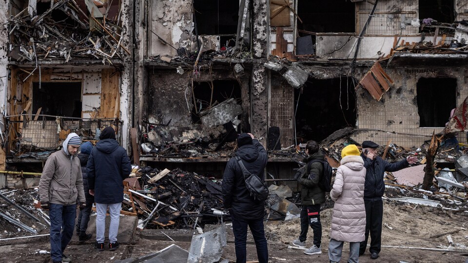 Des résidents de Kiev regardent le bâtiment complètement détruit.