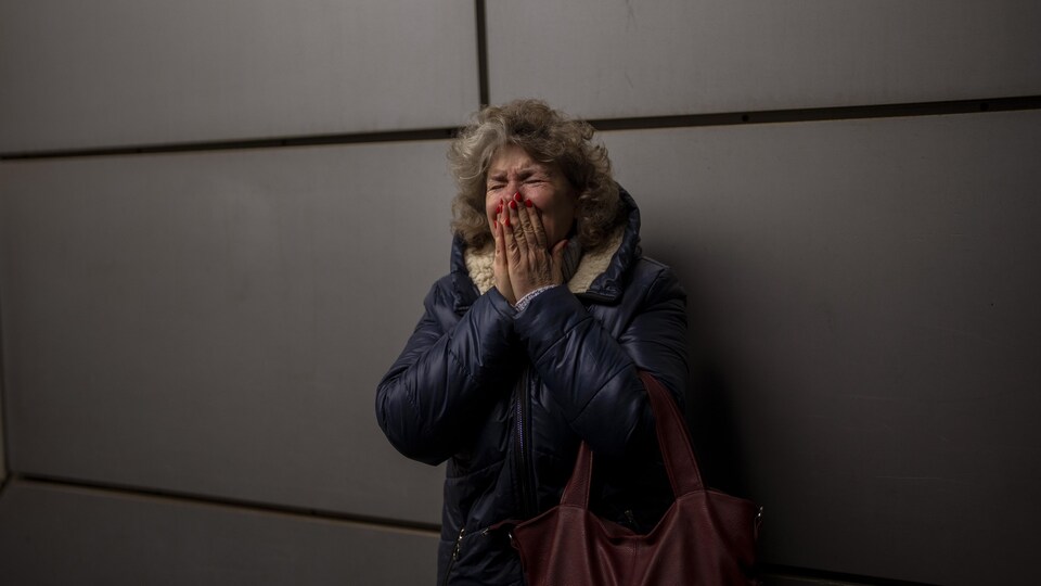 Une femme adossée à un mur est en pleurs.