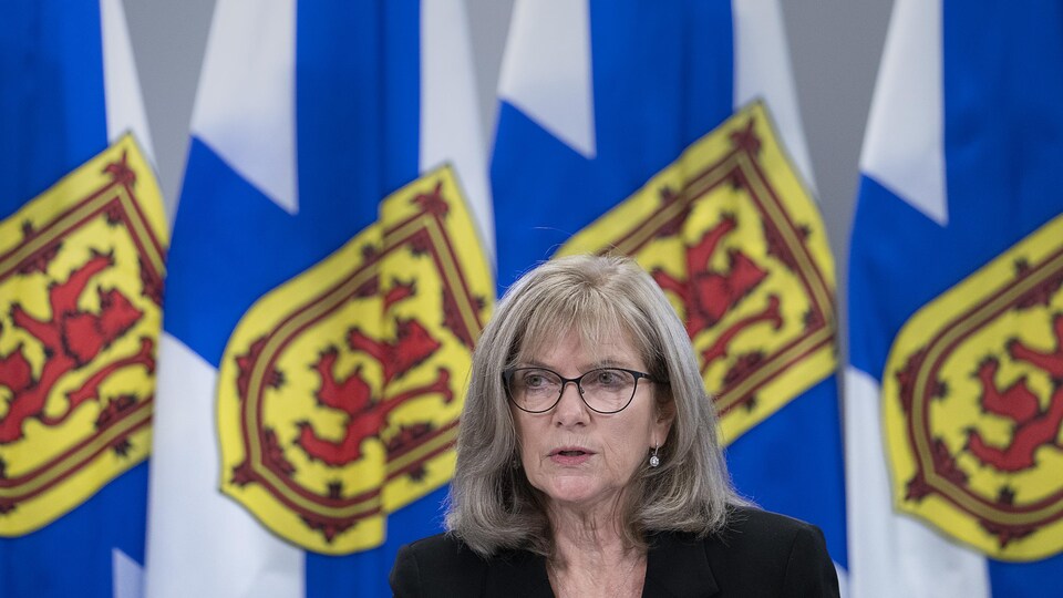 La vérificatrice générale est assise devant une rangée de drapeaux de la Nouvelle-Écosse.