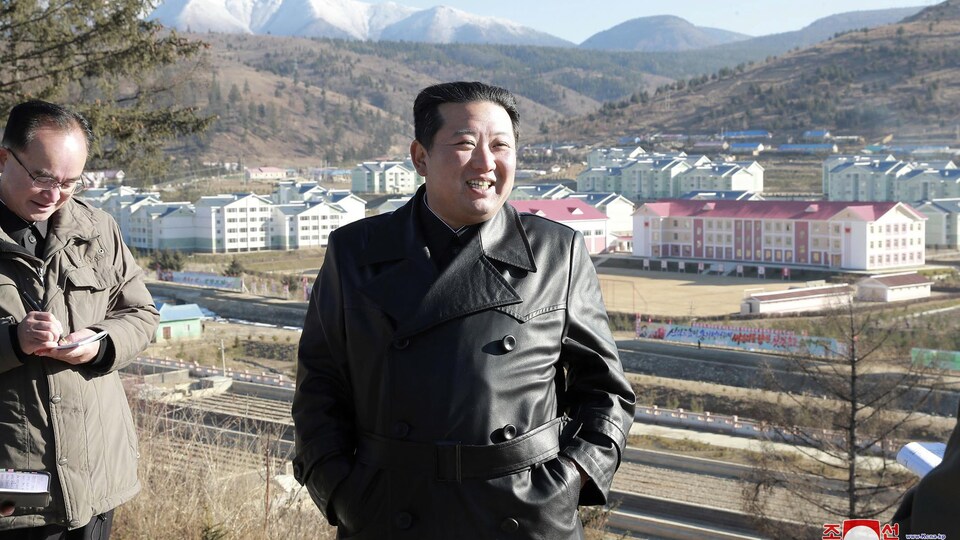 Kim Jong-un, surplombant une ville nouvelle, au pied de montagnes.