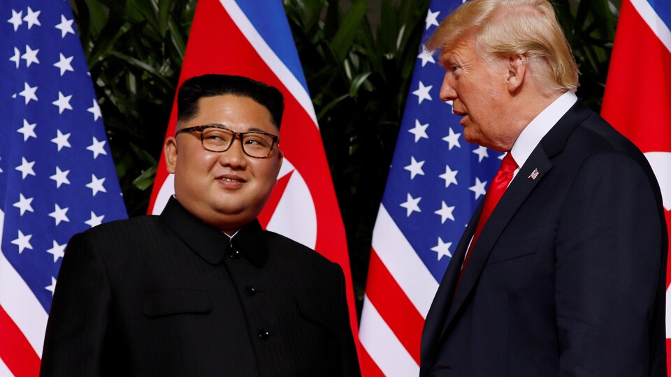 Kim Jong-un sourit en regardant au loin, à côté de Donald Trump.