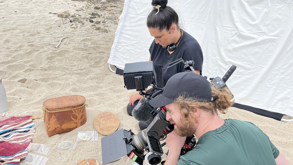 Une homme filme et une femme est assise à côté de lui.