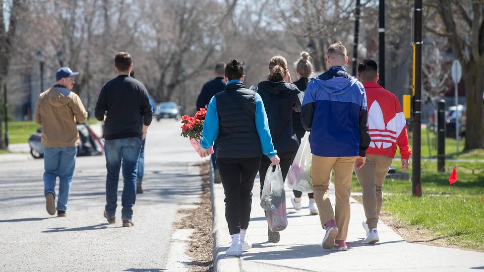 Cadets from behind, walking down the street. They were carrying flowers.
