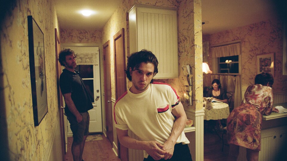 Un homme regarde la caméra dans un décor vieillot.