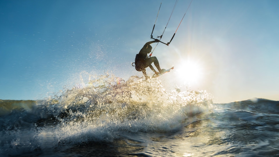 Un athlète de surf cerf-volant exécute un saut au-dessus de l'eau.