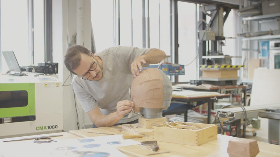 Martin Laberge sculpte la coque du casque sur une forme en argile.