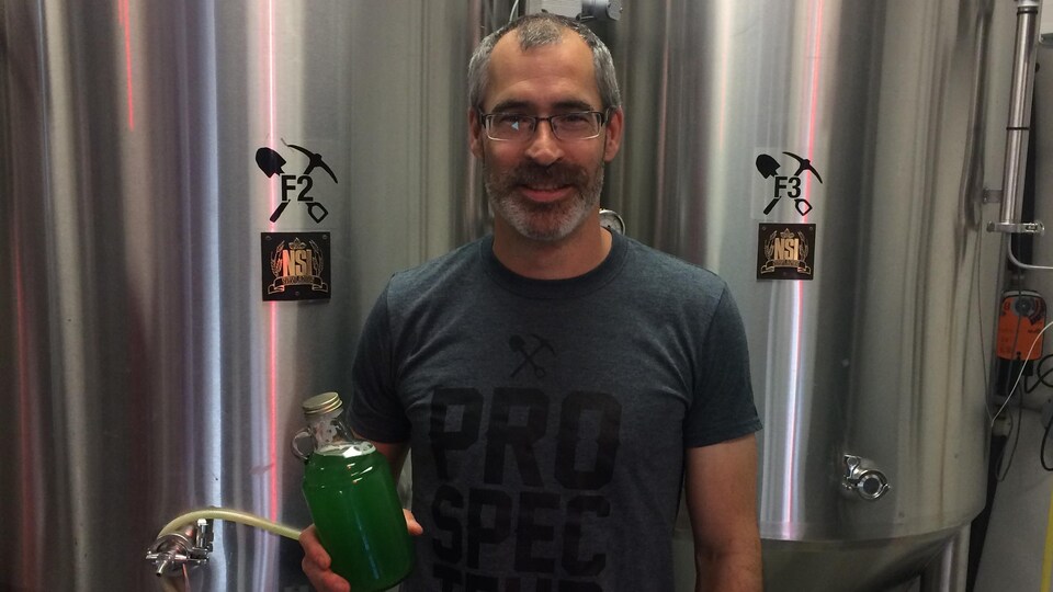 Yan Lapointe tient une bouteille de kombucha