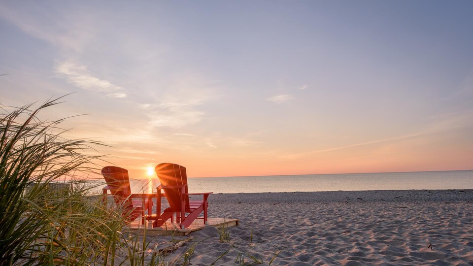 Des chaises rouges sur la plage Kellys alors que le soleil se lève.