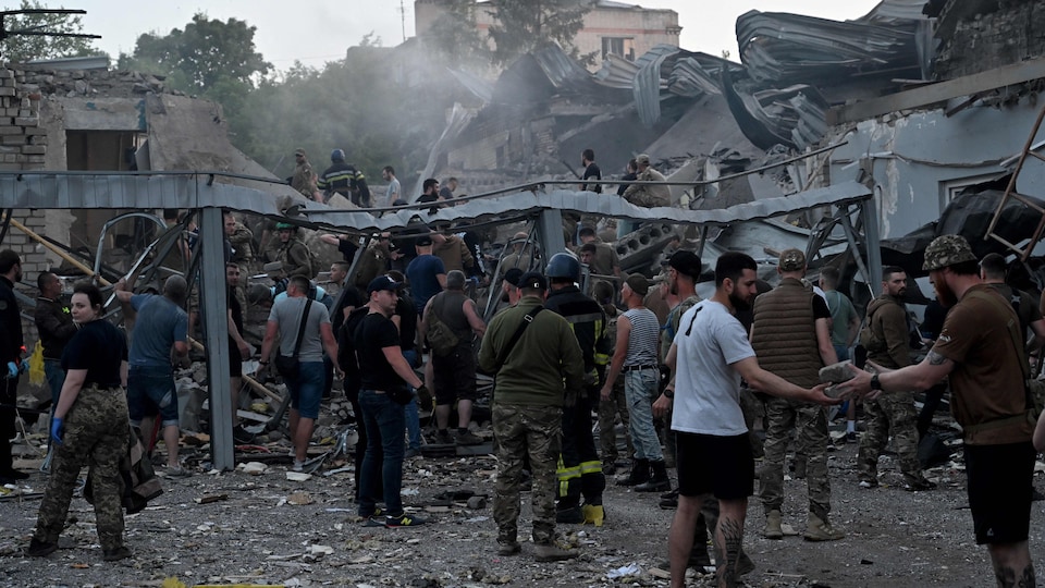 Des hommes s'activent sur les ruines d'un édifice.