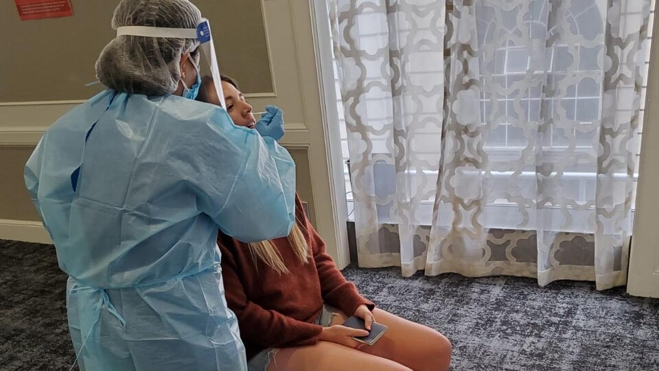 Une infirmière prélève un échantillon nasal.