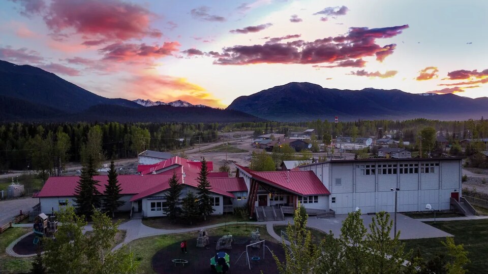 Le bâtiment de l'école Aatse Davie avec des montagnes en arrière-plan.