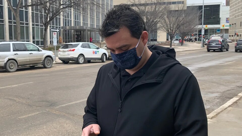 Kyle Alexander Pietz walks down the sidewalk in downtown Winnipeg and looks at his cell phone.