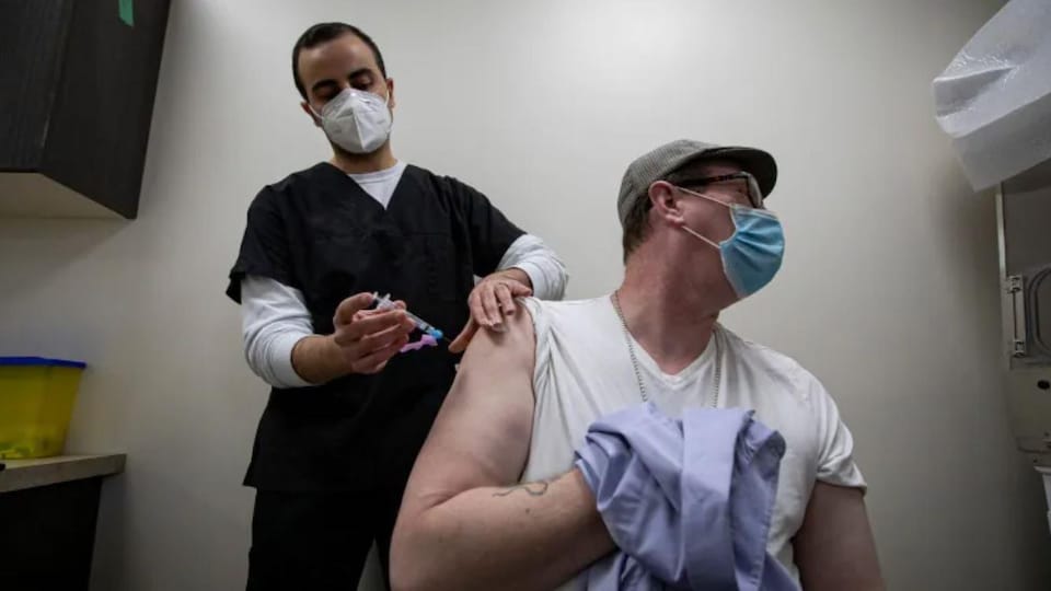 Un pharmacien administre une dose de vaccin à un patient.