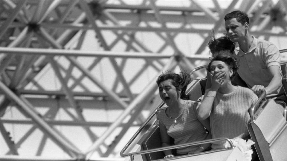 Quatre personnes prennent place dans un wagon d'un manège du parc d'attractions La Ronde, à Montréal.
