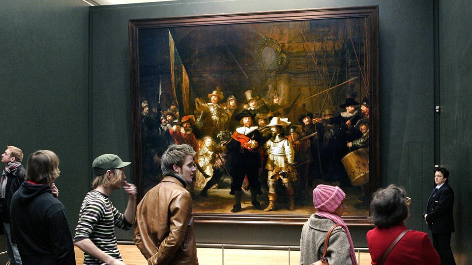 Plusieurs personnes se trouvent près du tableau «La ronde de nuit», peint par Rembrandt.