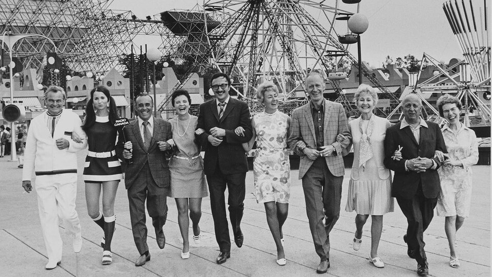 Les membres de l'équipe bras dessus, bras dessous, se promenant sur le site de La Ronde, avec La Grande Roue en arrière-plan.