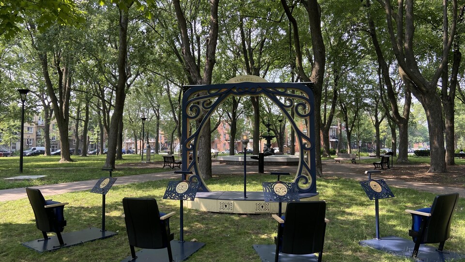 Des chaises et une scène sont installées dans un parc.
