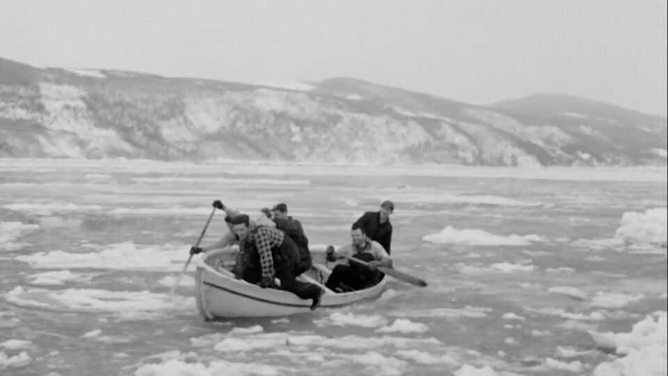 Cinq hommes dans un canot sur un lac gelé, dans une image en noir et blanc tirée d'un documentaire.