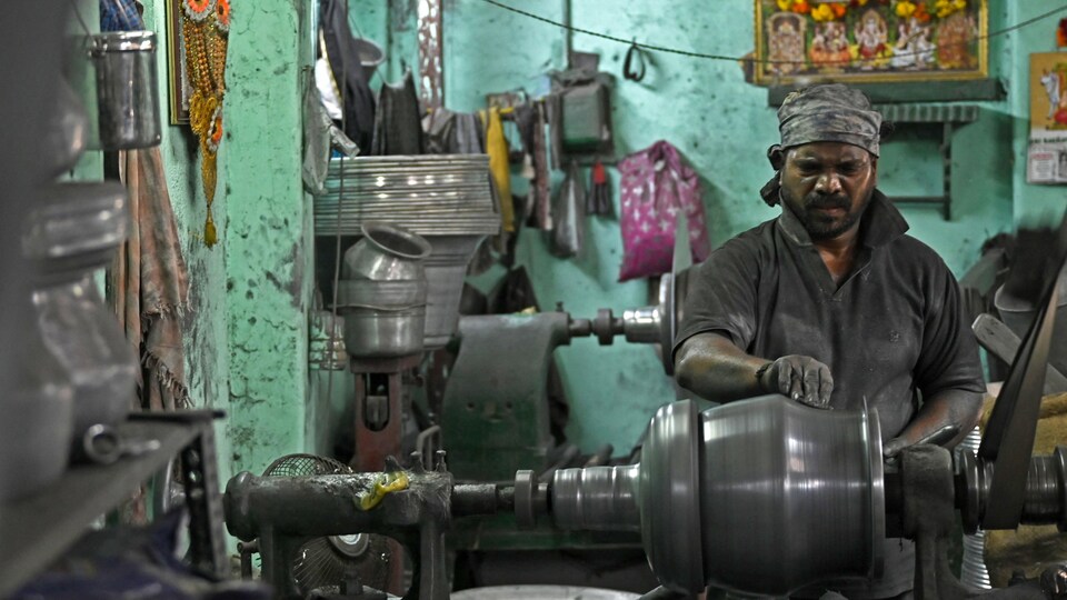 Un travailleur à l'ouvrage dans une usine de fabrication d'ustensiles en acier inoxydable. 