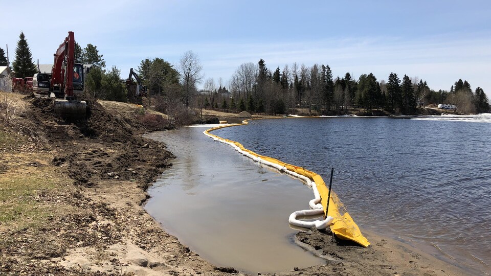 Une pelle mécanique creuse près d'un lac.