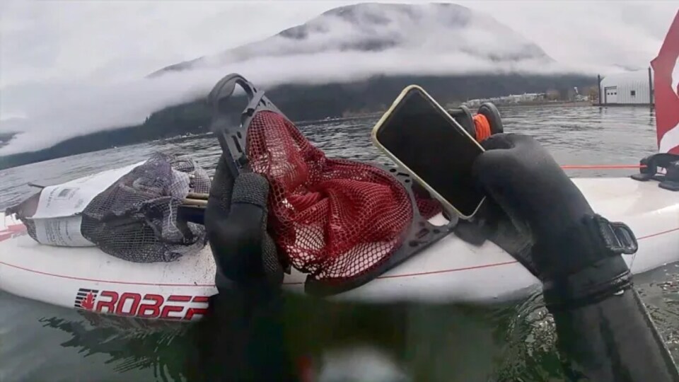 Un plongeur sort de l'eau un téléphone.
