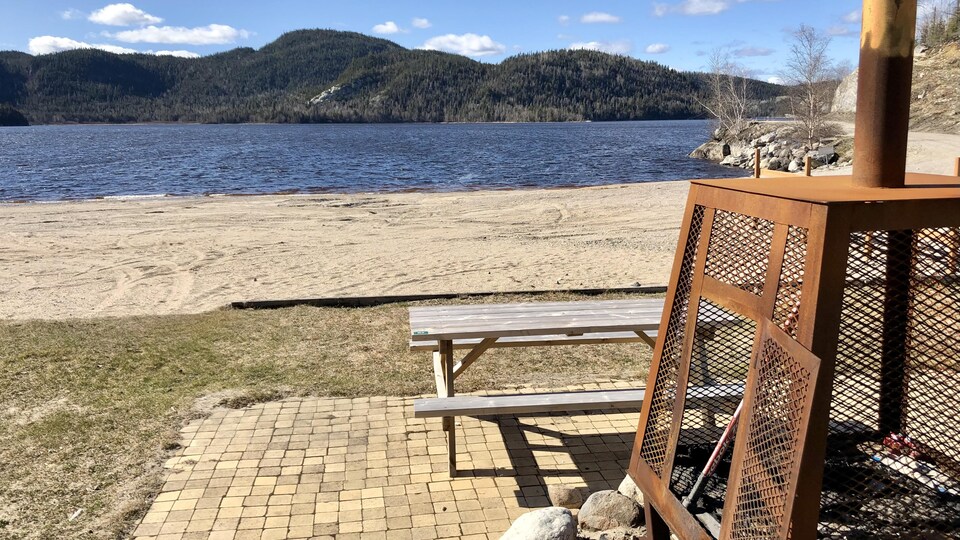Photo du lac avec en premier plan un foyer extérieur.