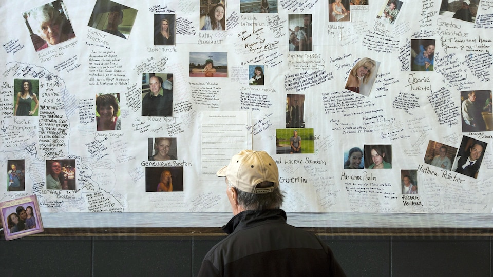 Un homme regarde des photos des victimes de la tragédie de Lac-Mégantic.