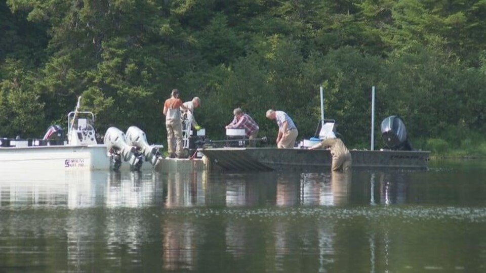 Des équipes enlèvent des barils de roténone des bateaux pour les emporter.