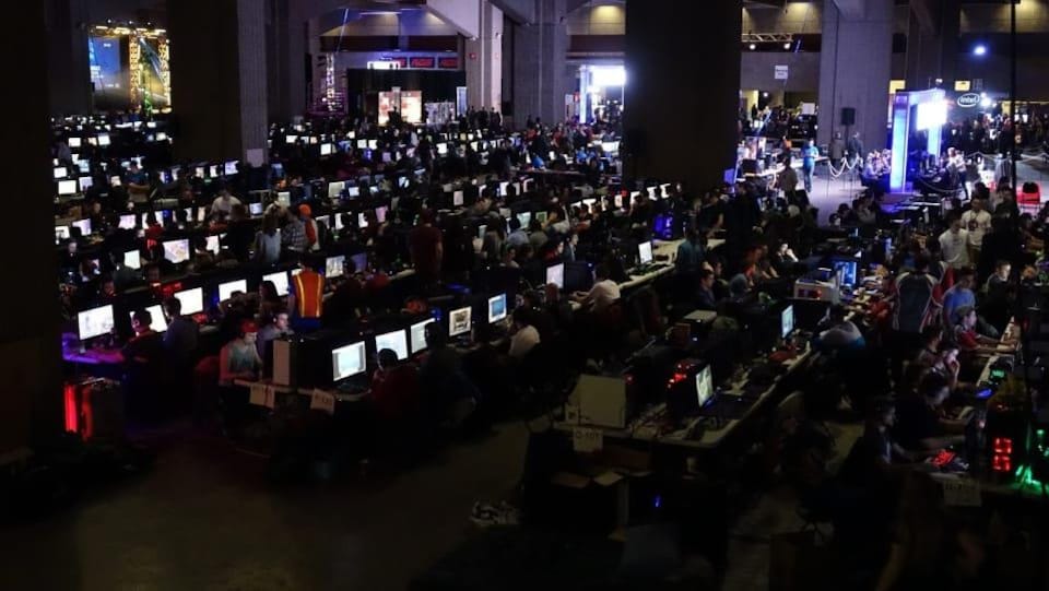 Quelques centaines de joueurs fourmillent dans une grande salle au travers des  rangées où sont installé les ordinateurs. 