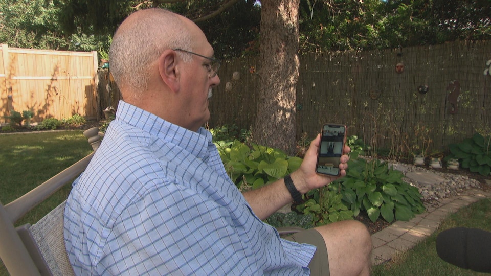 Larry Hill, assis dans sa cour arrière, en train de regarder une vidéo sur un iPhone.