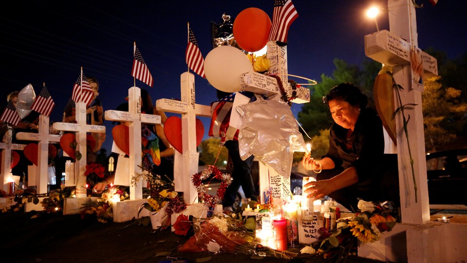 Une femme allume une chandelle devant l'une des croix représentant les victimes de la fusillade de Las Vegas.