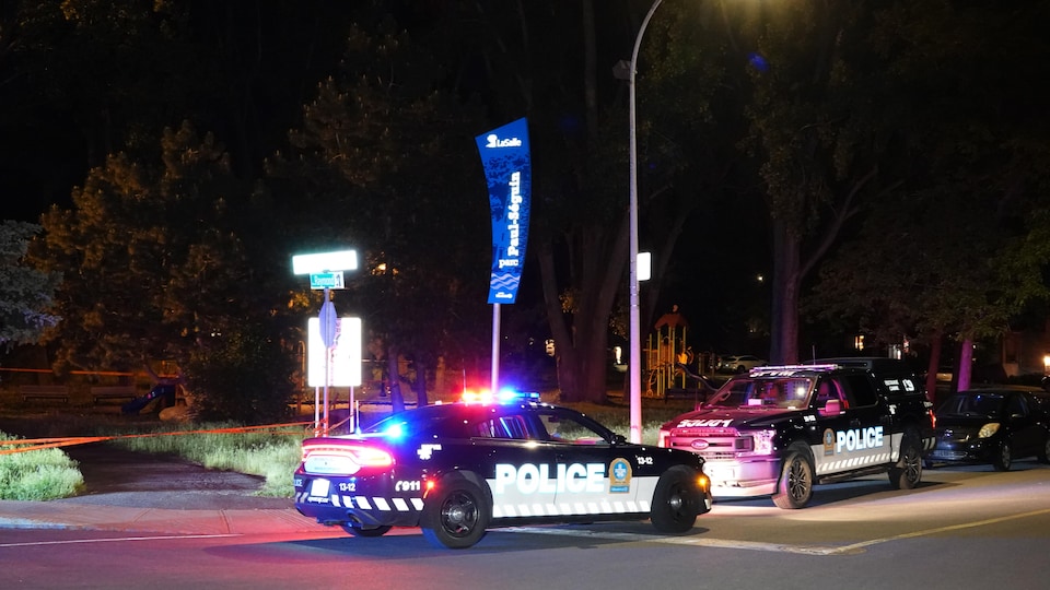 Des voitures du Service de police de la Ville de Montréal avec leurs gyrophares allumés la nuit.
