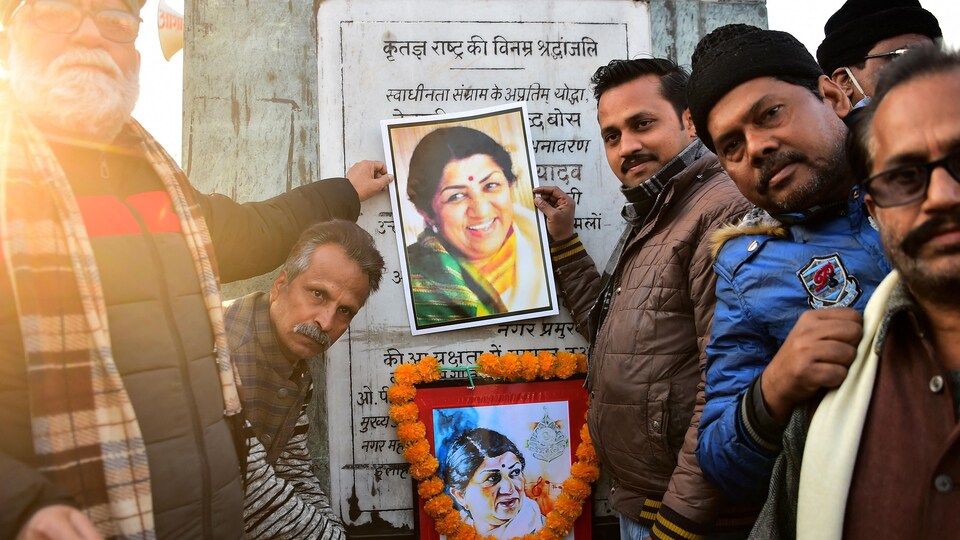 Des hommes devant une photo de la chanteuse Lata Mangeshkar.