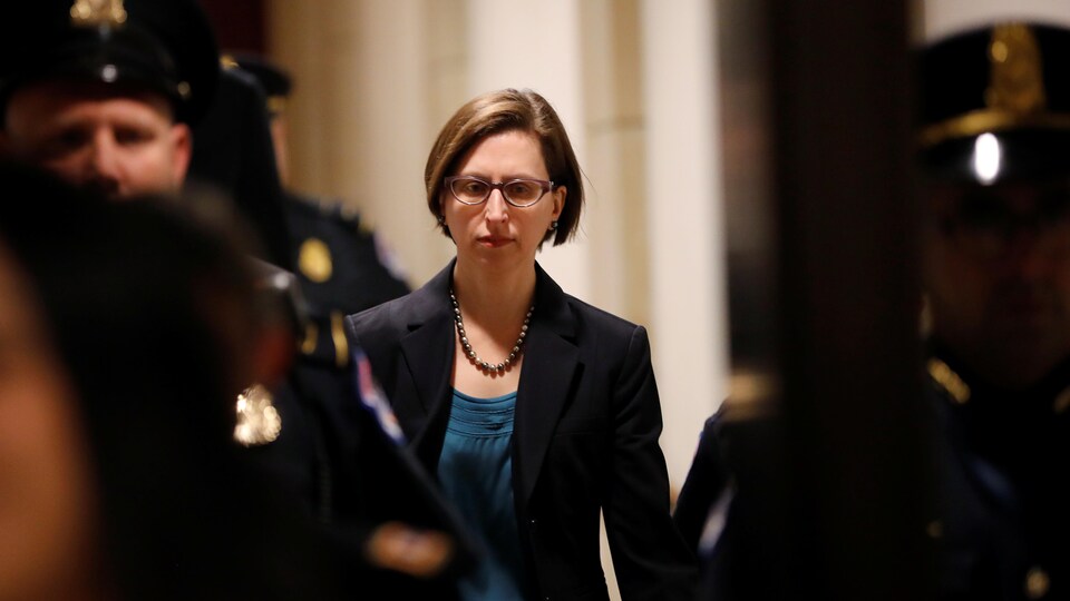 Portant des lunettes, Laura Cooper, marchant au Capitole, regarde vers le bas.