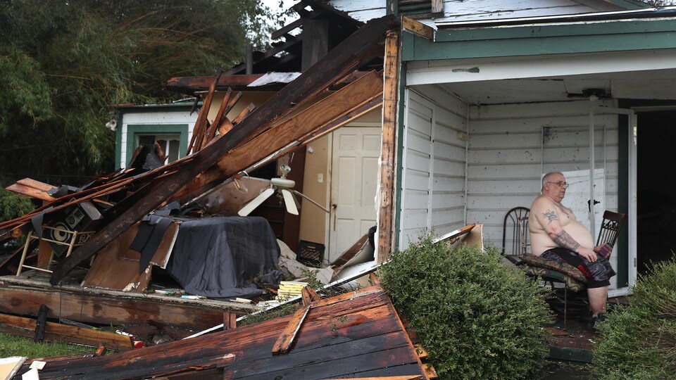 Chris Johnson assis sur le porche d'une maison en ruines. 