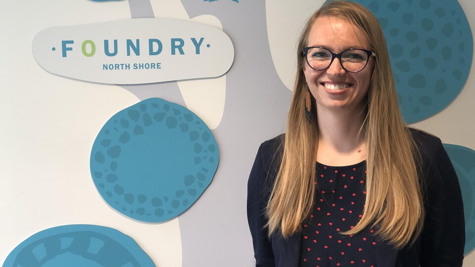 une femme devant un mur avec marqué foundry north shore