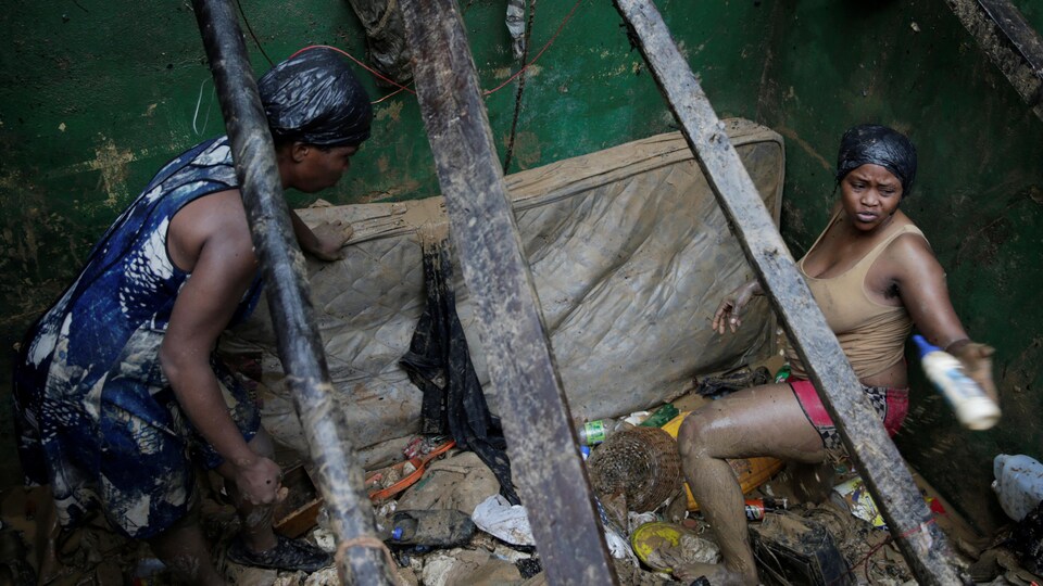 Une femme au milieu des détritus dans une pièce de sa maison.